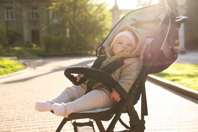Photo of Cute little baby in stroller at park on sunny day. Space for text