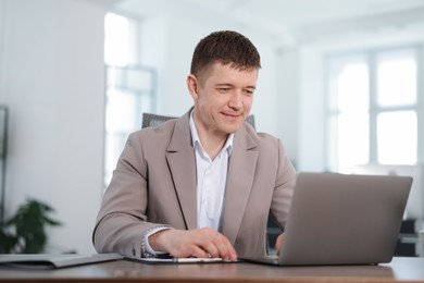 Photo of Man working on laptop at desk in office