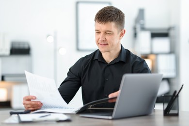 Photo of Handsome man working with documents at desk in office. Space for text