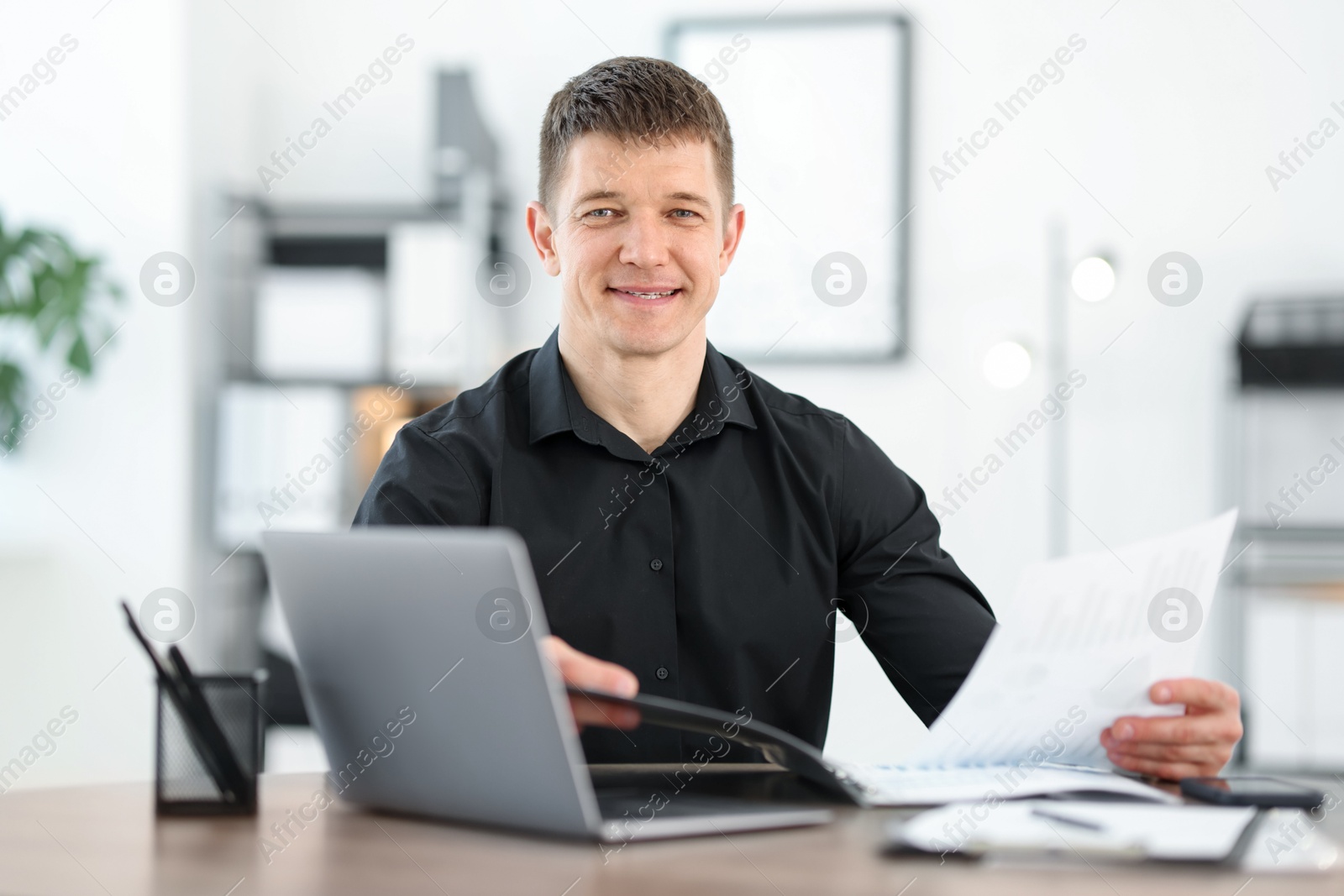 Handsome man working with documents at desk in office Photo of Handsome man working with documents at desk in office