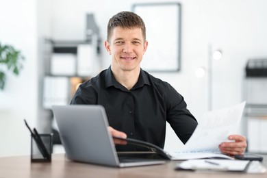 Photo of Handsome man working with documents at desk in office