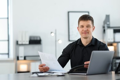 Photo of Handsome man working with documents at desk in office. Space for text