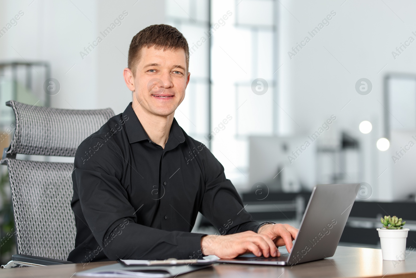 Man working on laptop at desk in office. Space for text Photo of Man working on laptop at desk in office. Space for text