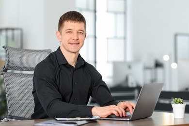Photo of Man working on laptop at desk in office. Space for text