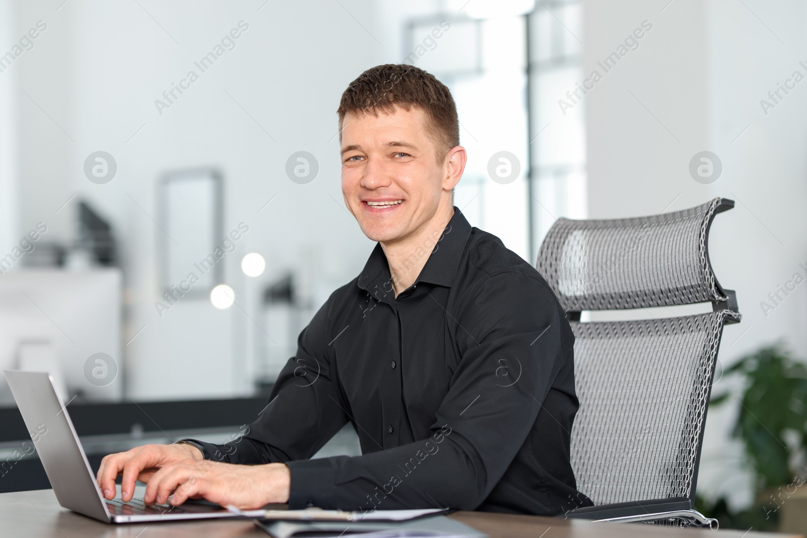 Photo of Man working on laptop at desk in office
