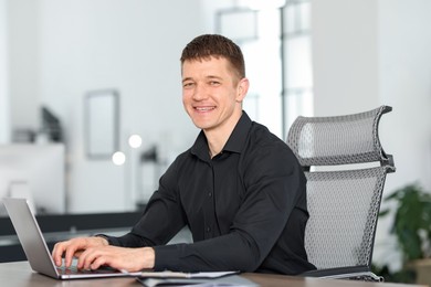 Photo of Man working on laptop at desk in office
