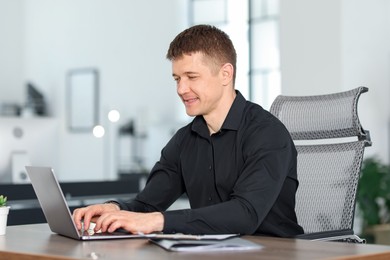 Photo of Man working on laptop at desk in office