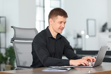 Photo of Man working on laptop at desk in office
