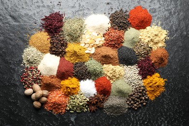 Photo of Many different spices on dark table, flat lay