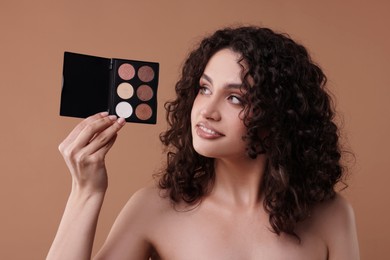 Photo of Smiling woman with eyeshadow palette on beige background