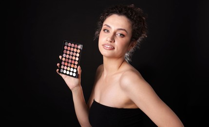 Photo of Woman with eyeshadow palette on black background