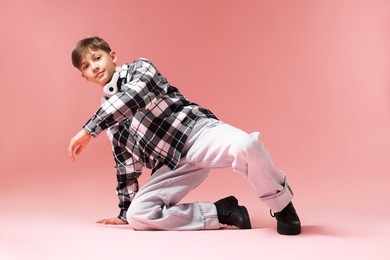 Photo of Boy with headphones in stylish clothes dancing on pink background