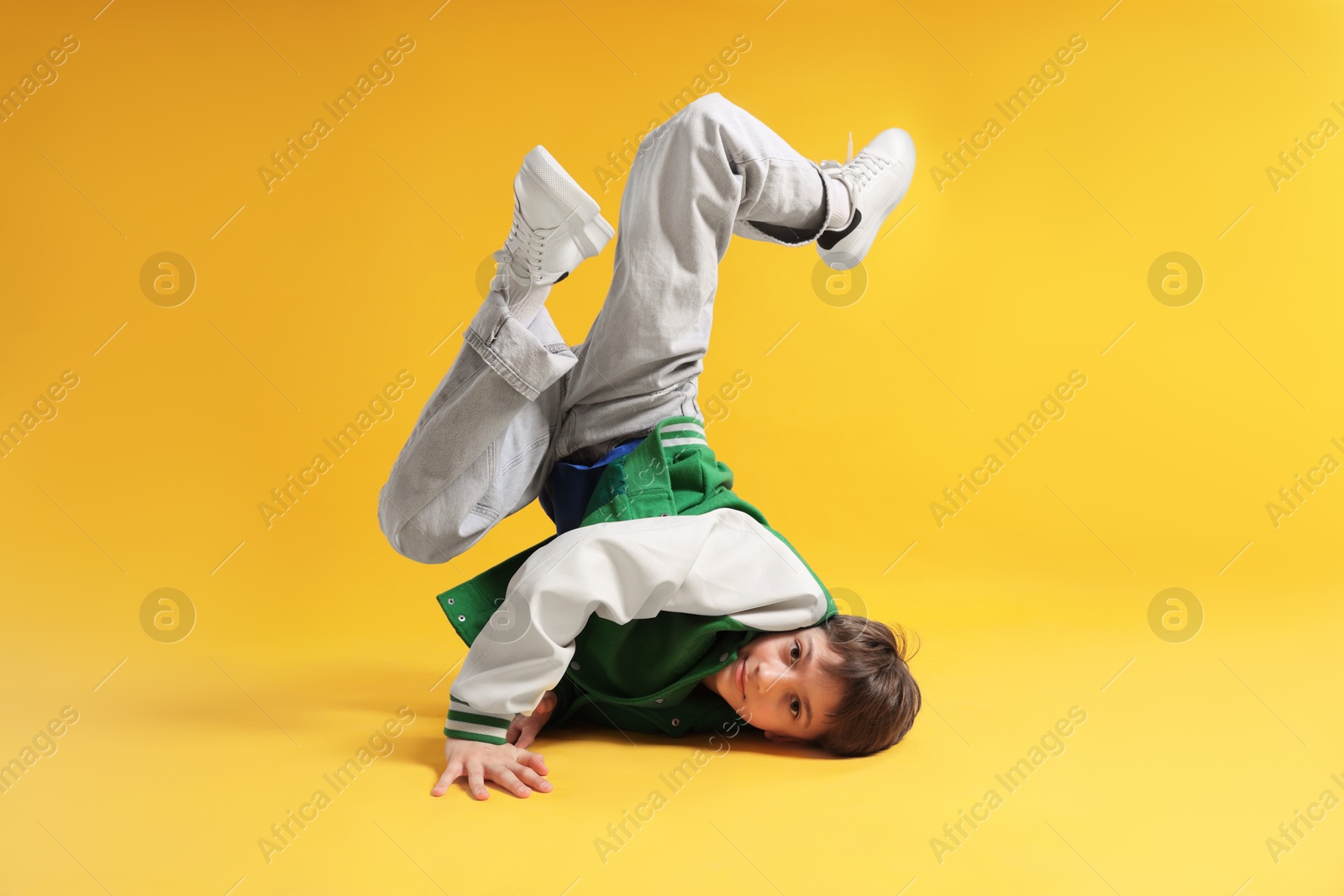 Boy in stylish clothes dancing on orange background Photo of Boy in stylish clothes dancing on orange background