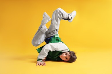 Photo of Boy in stylish clothes dancing on orange background