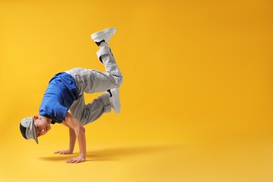 Photo of Boy in stylish clothes dancing on orange background, space for text