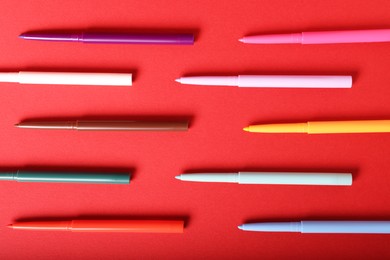 Photo of Colorful twist up eye pencils on red background, flat lay