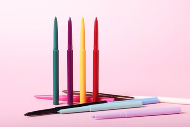 Photo of Colorful twist up eye pencils on pink background, closeup