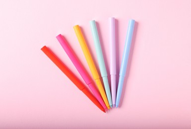 Photo of Colorful twist up eye pencils on pink background, flat lay