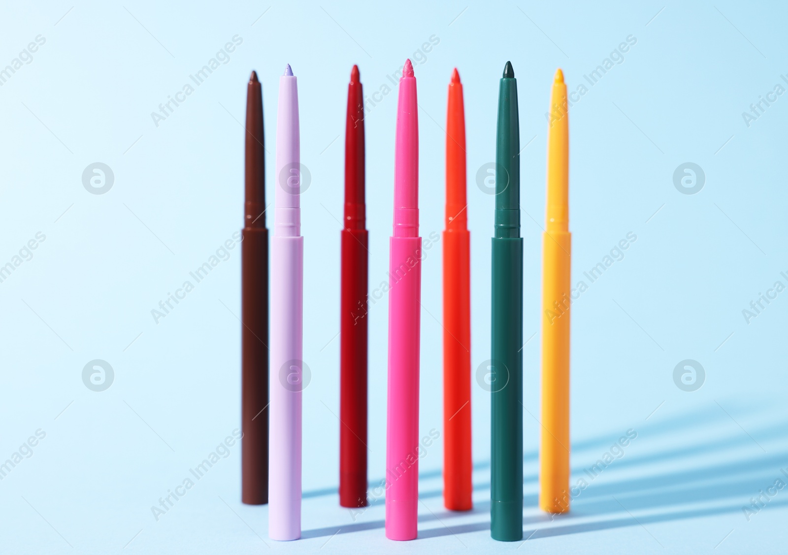 Colorful twist up eye pencils on light blue background Photo of Colorful twist up eye pencils on light blue background