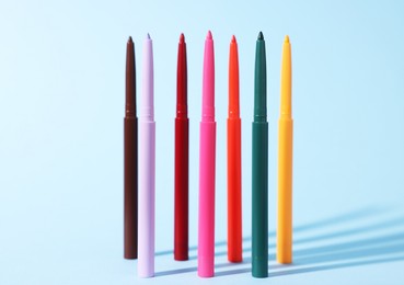 Photo of Colorful twist up eye pencils on light blue background