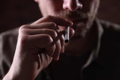 Photo of Man smoking cigarette on blurred background, closeup