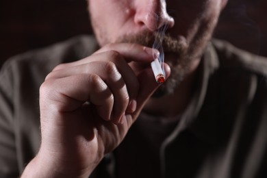 Photo of Man smoking cigarette on blurred background, closeup