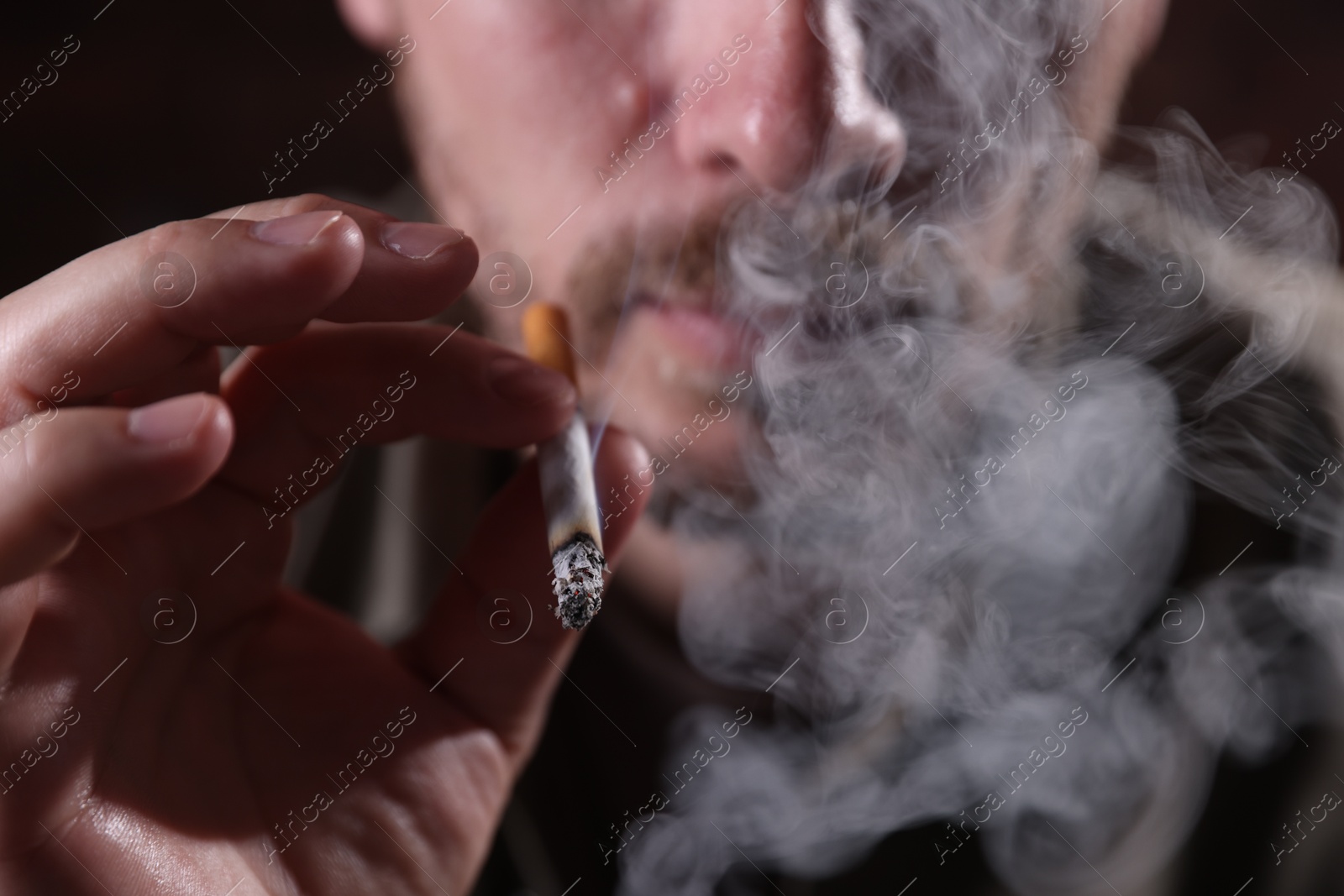 Man smoking cigarette on blurred background, closeup Photo of Man smoking cigarette on blurred background, closeup