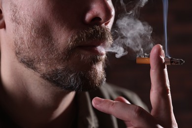 Photo of Man smoking cigarette on blurred background, closeup