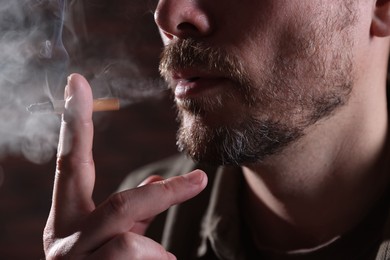 Photo of Man smoking cigarette on blurred background, closeup