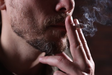 Photo of Man smoking cigarette on blurred background, closeup