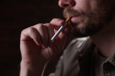 Photo of Man smoking cigarette on blurred background, closeup