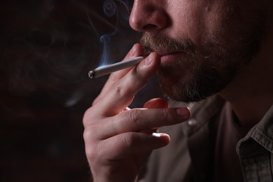 Photo of Man smoking cigarette on blurred background, closeup