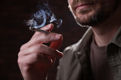 Photo of Man smoking cigarette on blurred background, closeup