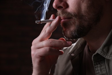 Photo of Man smoking cigarette on blurred background, closeup
