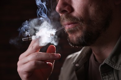 Photo of Man smoking cigarette on blurred background, closeup