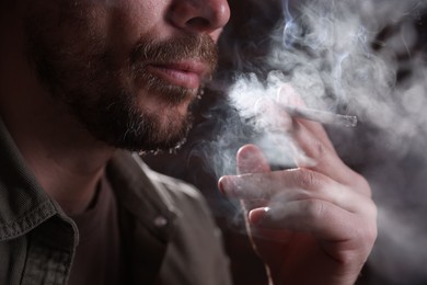 Photo of Man smoking cigarette on blurred background, closeup