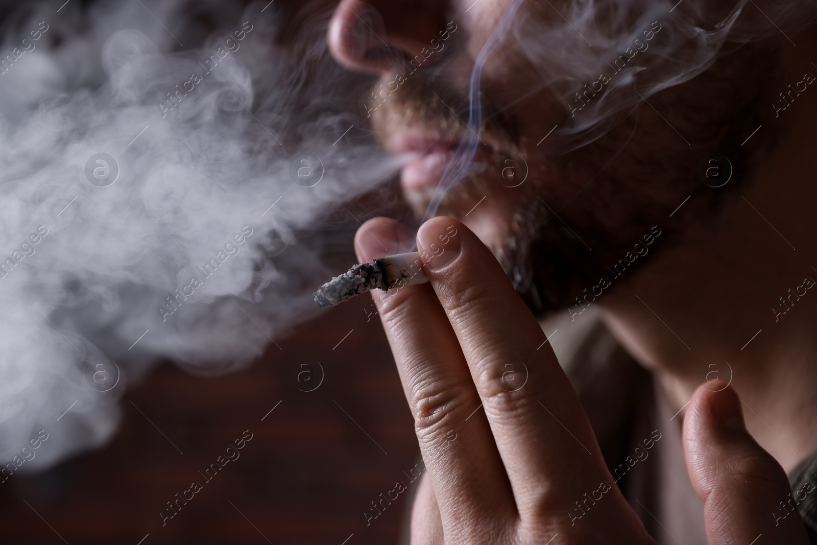 Man smoking cigarette on blurred background, closeup Photo of Man smoking cigarette on blurred background, closeup
