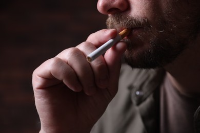 Photo of Man smoking cigarette on blurred background, closeup