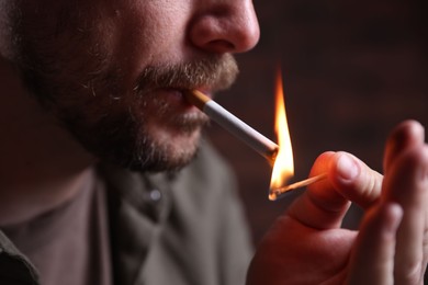 Photo of Man lighting cigarette with match on blurred background, closeup