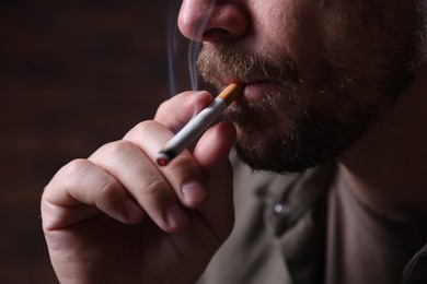 Photo of Man smoking cigarette on blurred background, closeup