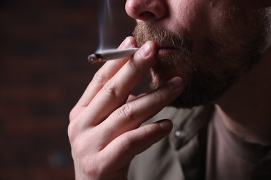 Photo of Man smoking cigarette on blurred background, closeup