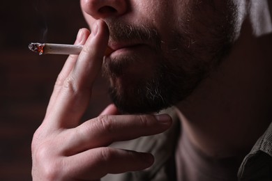 Photo of Man smoking cigarette on blurred background, closeup