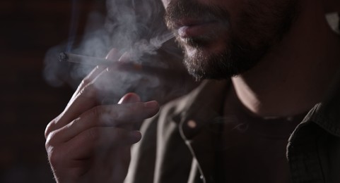 Photo of Man smoking cigarette on blurred background, closeup