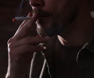 Photo of Man smoking cigarette on blurred background, closeup
