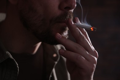 Photo of Man smoking cigarette on blurred background, closeup