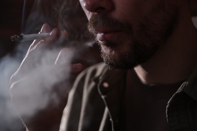 Photo of Man smoking cigarette on blurred background, closeup
