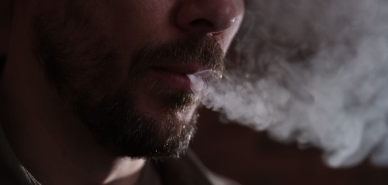 Photo of Man smoking on blurred background, closeup view