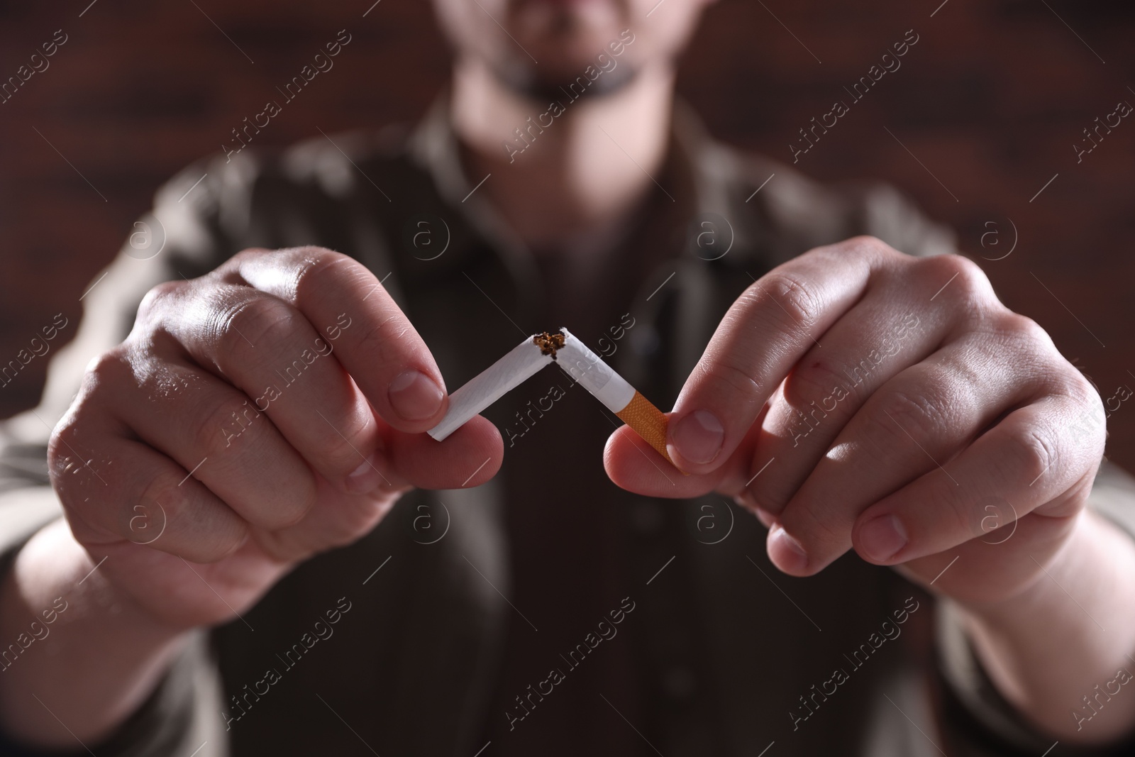 Man holding broken cigarette on blurred background, closeup. Stop smoking Photo of Man holding broken cigarette on blurred background, closeup. Stop smoking