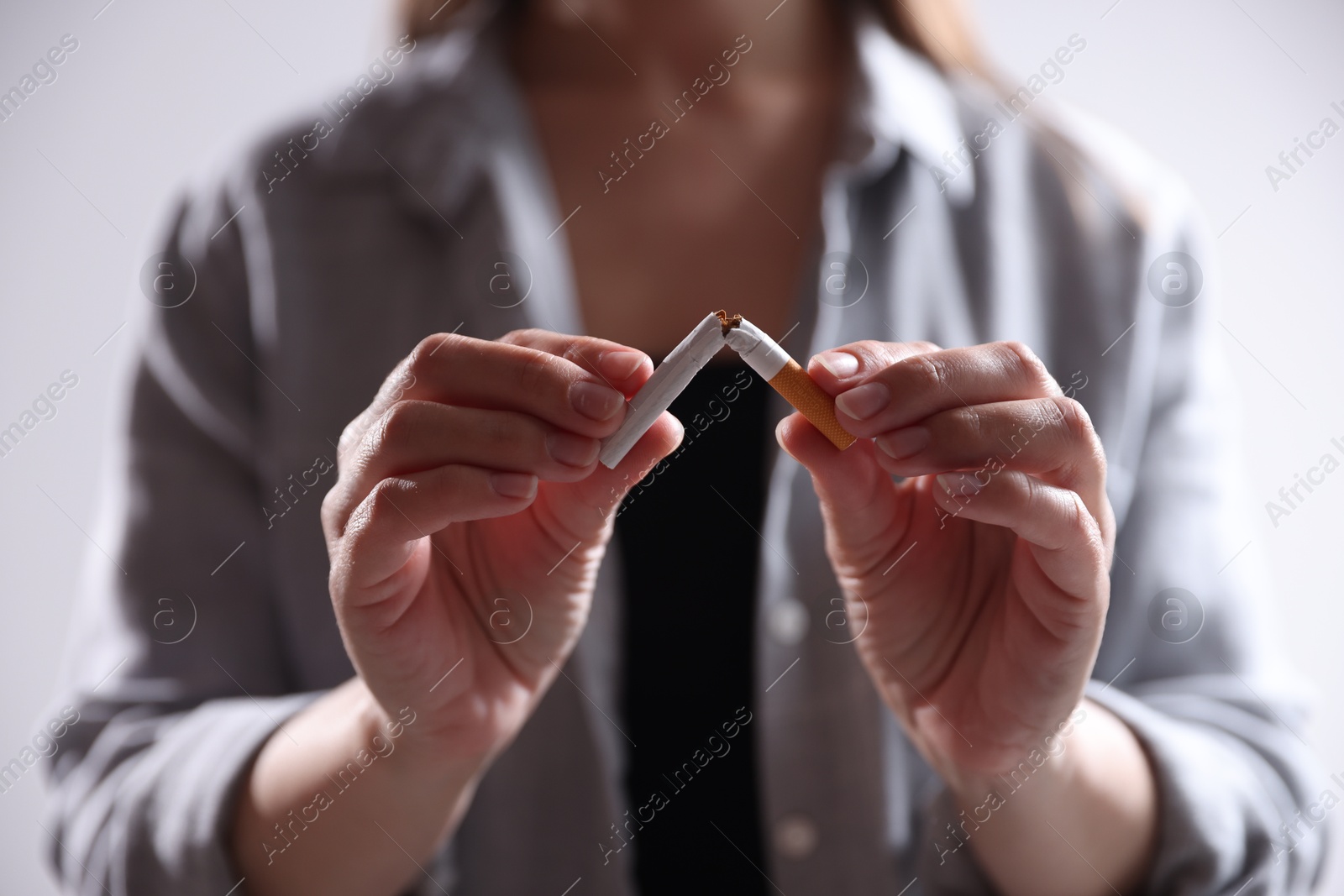 Woman holding broken cigarette on light background, closeup. Stop smoking Photo of Woman holding broken cigarette on light background, closeup. Stop smoking