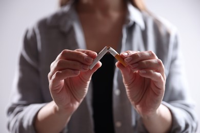 Photo of Woman holding broken cigarette on light background, closeup. Stop smoking